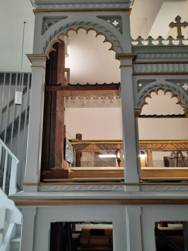 Blick durch das leere Gehäuse der Orgel auf die rückwärtige Kirchenwand.